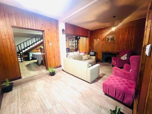 ein Wohnzimmer mit einer weißen Couch und rosa Stühlen in der Unterkunft Serendib Hotel in Nuwara Eliya