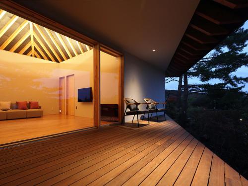 a room with a deck with a couch and a television at Spagreenness in Kokonoe