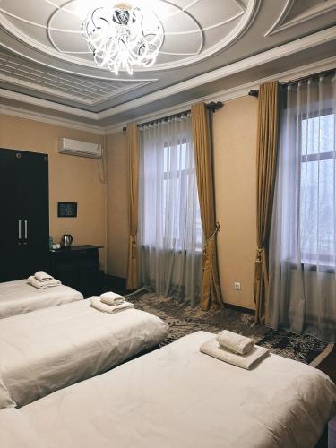 ドゥシャンベにあるCITY GARDEN HOTELのベッド2台とシャンデリアが備わるホテルルームです。