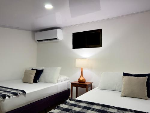 a bedroom with two beds and a tv on the wall at Casa Caoba AC near Guanacaste Airport in Liberia
