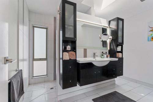 a white bathroom with a sink and a mirror at Tauranga Luxury Getaway in Tauranga