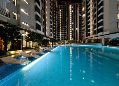 uma grande piscina com cadeiras e edifícios em K Avenue Cozy Family Suites 4-6 pax 亚庇国际机场5分钟 em Donggongon