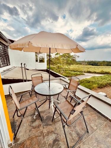 eine Terrasse mit einem Tisch, Stühlen und einem Sonnenschirm in der Unterkunft Casa de Descanso Excelente Ubicación Villavicencio in Villavicencio