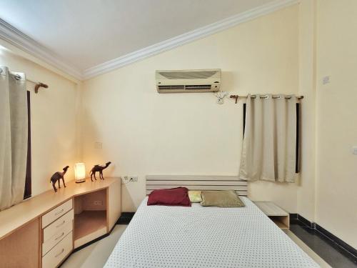 a bedroom with a bed and a desk with a air conditioner at Park Breeze Penthouse in Bangalore