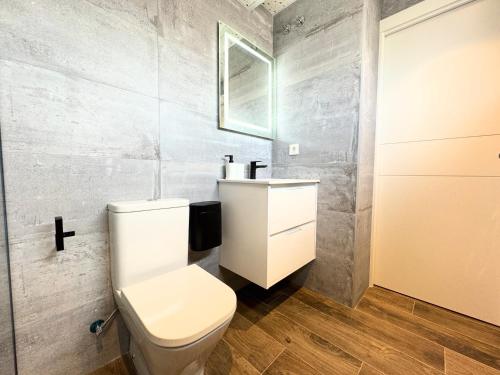 a bathroom with a white toilet and a sink at Apartamentos Identia Sport by gaiarooms in León