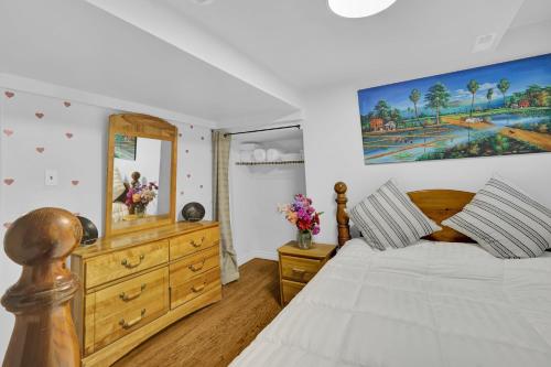 een slaapkamer met een bed, een dressoir en een spiegel bij Cozy Lower Level 2BR Apartment in Barrie