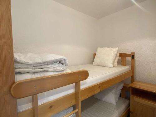 Cette petite chambre comprend des lits superposés avec des draps blancs. dans l'établissement Charmant studio 4 pers, balcon sud, quartier Éclose, proche commerces et Alpe Express, animaux admis - FR-1-405-356, à Huez