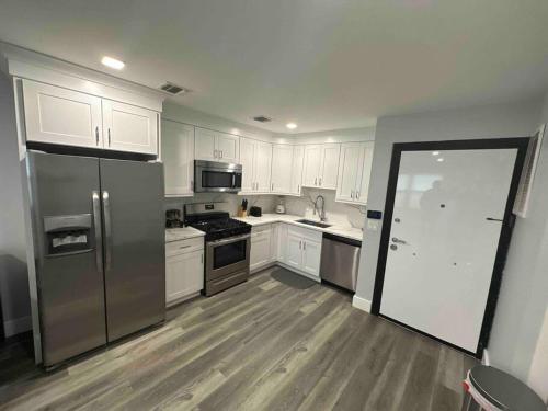 uma cozinha com armários brancos e um frigorífico de aço inoxidável em The Homey Suite - 1BR with Luxe Amenities em Paterson