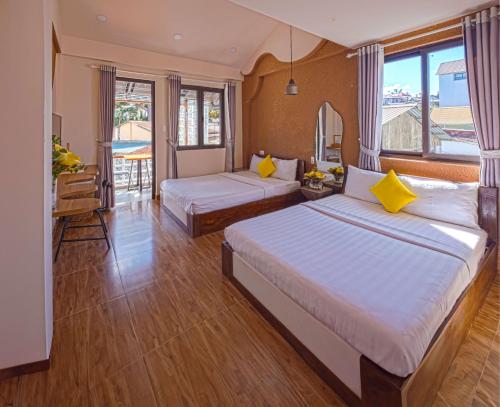 a hotel room with two beds and a balcony at Mayy House Dalat in Da Lat