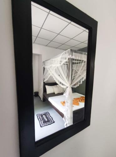 a mirror on a wall with a bed in a room at AURORA Midigama in Ahangama