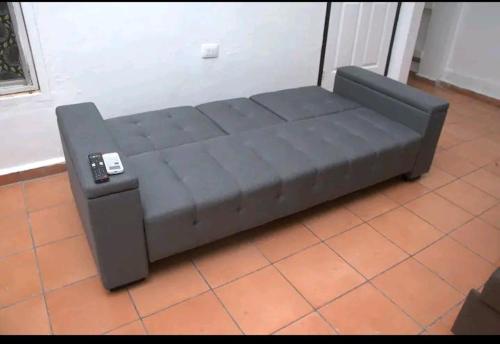 un sofá negro con mando a distancia sentado en un suelo de baldosa en Relax sin ruidos centrico., en Santa Rosa de Copán
