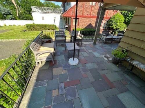 an outdoor patio with benches and an umbrella at Serene Stay - Stylish House Close to NYC in Paterson