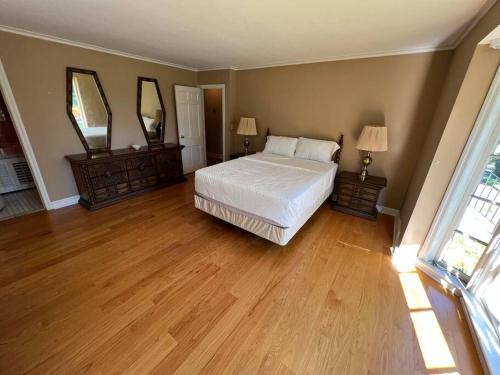 a bedroom with a white bed and two mirrors at Serene Stay - Stylish House Close to NYC in Paterson