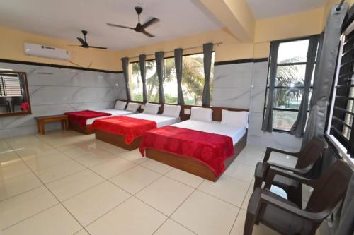 a bedroom with two beds with red sheets and windows at Ocean View in Māvalli