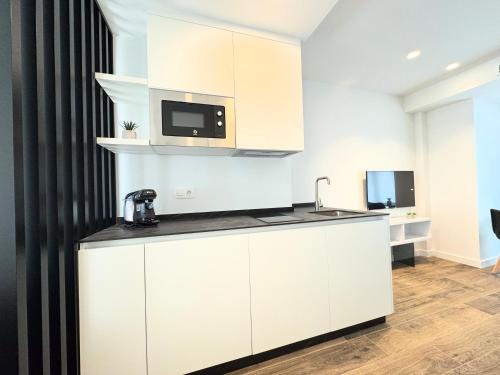 a kitchen with white cabinets and a microwave at Apartamentos Identia Sport by gaiarooms in León