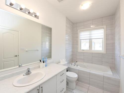 La salle de bains blanche est pourvue d'une baignoire, de toilettes et d'un lavabo. dans l'établissement Stylish Home in Waterdown, à Hamilton