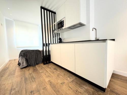 a kitchen with white cabinets and a wooden floor at Apartamentos Identia Sport by gaiarooms in León