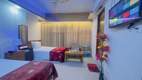 a hotel room with two beds and a flat screen tv at Hotel Blue Sky Mirpur in Dhaka
