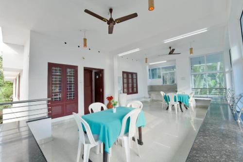 une salle à manger avec une table bleue et des chaises blanches dans l'établissement Hilton Beach Home, à Alappuzha