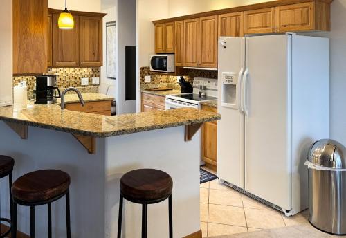 a kitchen with a white refrigerator and wooden cabinets at A quiet, stylish and cozy retreat. in Page