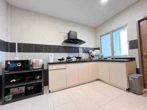 a kitchen with white cabinets and a microwave at AJ Homestay Near Kuching Airport in Kuching