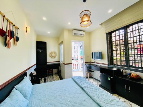 a bedroom with a bed and a desk and a television at SAM HOMESTAY HUE in Hue