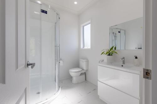 a white bathroom with a shower and a toilet at Oasis Rural Retreat in Norsewood