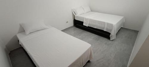 two beds in a room with white walls at Los Pinos in Jardin
