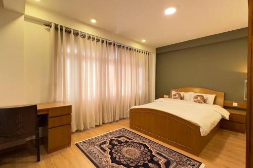um quarto com uma cama, uma secretária e uma televisão em 21 Tara Apartments em Kathmandu