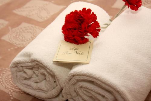 a red flower on a towel with a note at Villa Germânia in Balneário Camboriú