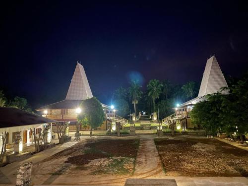 un grupo de edificios con agujas blancas por la noche en Rumah Budaya Sumba, en Lokokaki