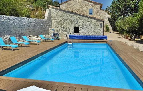une piscine avec des chaises bleues et un bâtiment dans l'établissement Le Mas Veissiere, à Lussan
