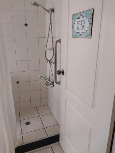 un baño con ducha y una puerta con un cartel. en Red Cottage. 2 ROOM FOR 1. BEDROOM+Private Kithenette, Lounge, TV, Fridge room en Harristown