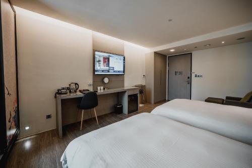 a hotel room with a bed and a desk and a television at Hub Hotel Kaohsiung Yawan Branch in Kaohsiung