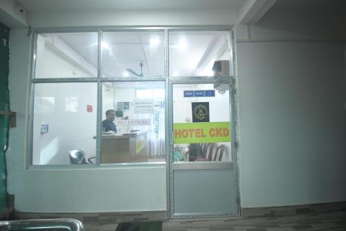 ein Glasfenster eines Hotelshop mit einer Person darin in der Unterkunft HOTEL CKD in Gogāmukh