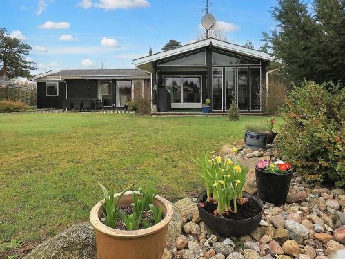 a house with pots of plants in a yard at 4 star holiday home in Væggerløse-By Traum in Bøtø By