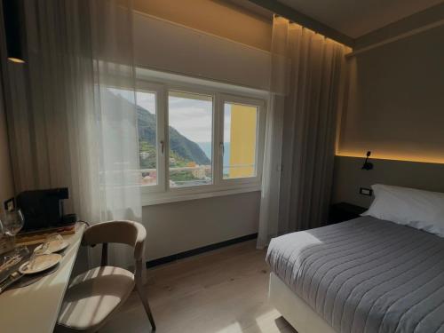 Schlafzimmer mit einem Bett, einem Schreibtisch und einem Fenster in der Unterkunft The Upper House in Riomaggiore