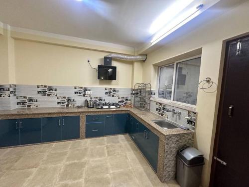 a large kitchen with blue cabinets and a sink at Monkey Temple Apartment in Kathmandu