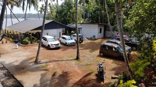 a group of cars parked in a parking lot with palm trees at Sambranikodi Lagoongate Resorts in Perumanseri