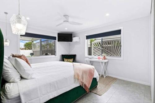 Un dormitorio blanco con una cama y dos ventanas. en Pet Friendly Beach House with pool - Sleeps 10, en Urangan
