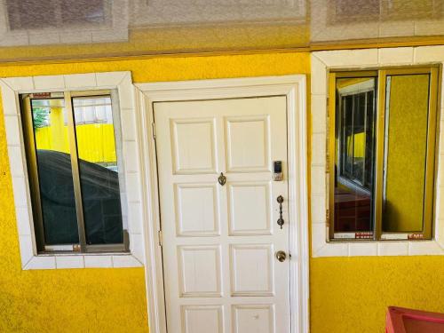 eine weiße Tür und zwei Fenster an einer gelben Wand in der Unterkunft Destination Hope Booking in Georgetown