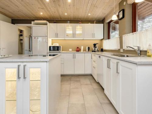 a kitchen with white cabinets and white appliances at 6 person holiday home in R dby in Rødby