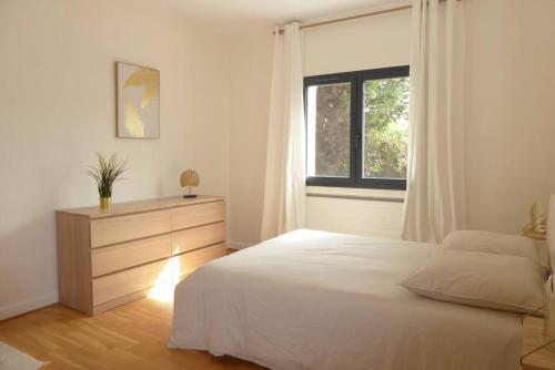 a bedroom with a bed and a dresser and a window at La Villa des Pins avec piscine et tennis in Garons