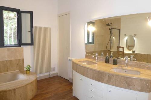 a bathroom with two sinks and a large mirror at La Villa des Pins avec piscine et tennis in Garons