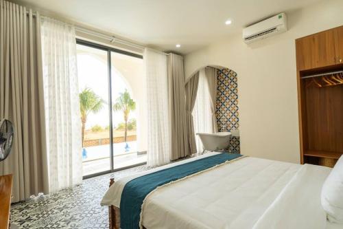 sypialnia z dużym łóżkiem i dużym oknem w obiekcie Amanda villa 4 Phan Thiết w mieście Mui Ne