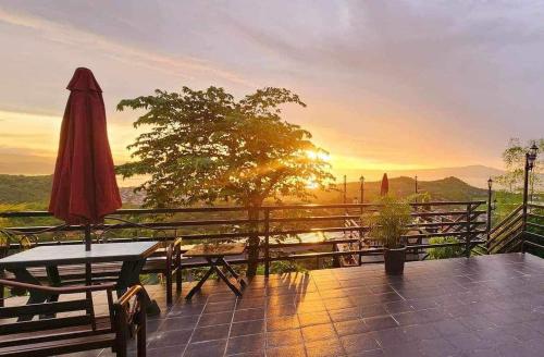 a patio with a table and an umbrella and a sunset at ROCCA Del GARDA Residences in Binangonan