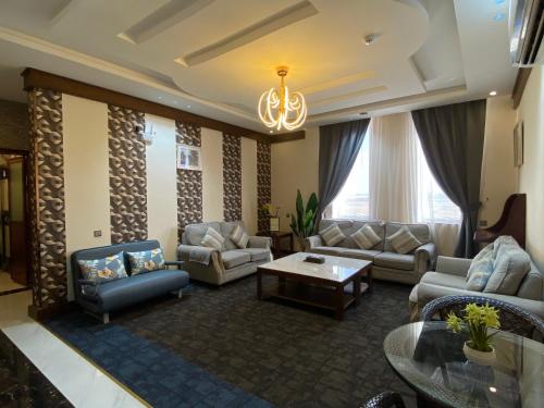 uma ampla sala de estar com sofás e um lustre em Aral Hotel Apartments em Tabuk