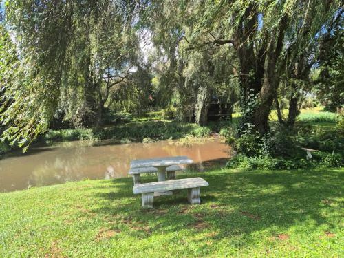 a park bench sitting in the grass near a pond at Air Lakehouse in Hilton