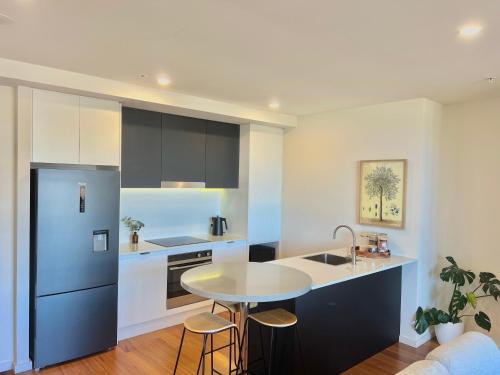 a kitchen with a table and a refrigerator at Harbour Towers, Newcastle's Luxe Apartment Stays in Newcastle