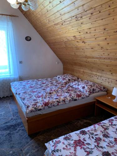 a bedroom with two beds and a wooden wall at Chata Astrička in Stará Lesná